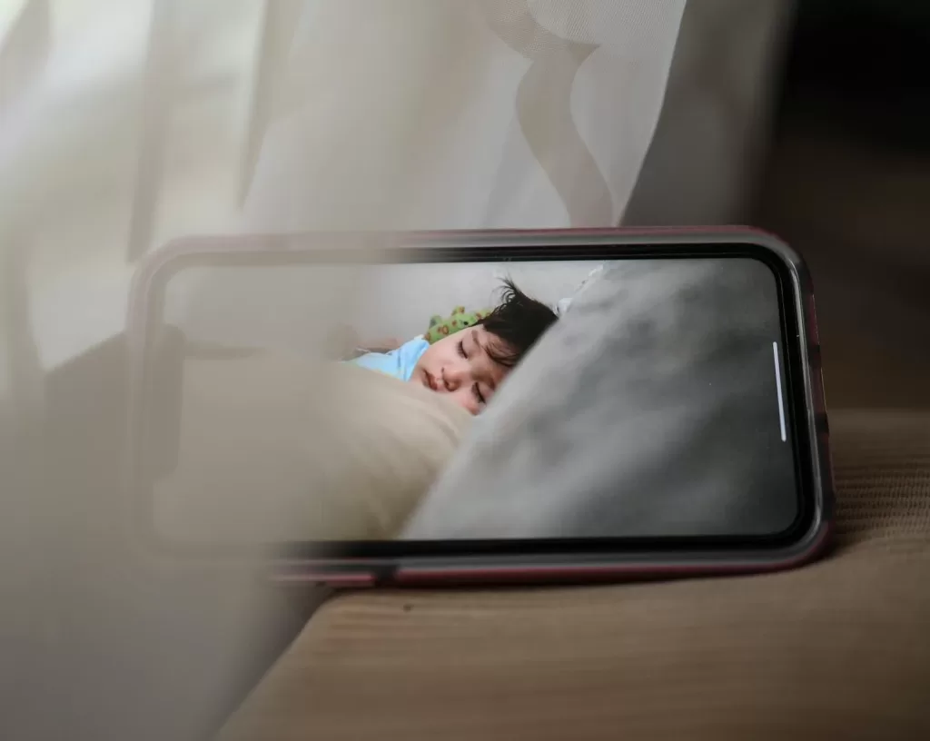 Finding Peace of Mind: Choosing the Best Video Baby Monitor in India A smartphone displaying a sleeping baby in a cozy, indoor setting, conveying warmth and care.