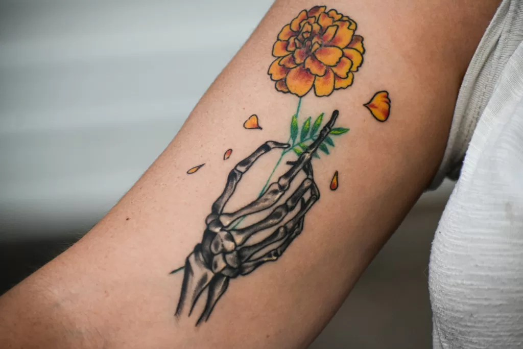 Best Tattoo Inks in India: The Ultimate Artist's Buying Guide A person with a tattoo on their arm holding a flower