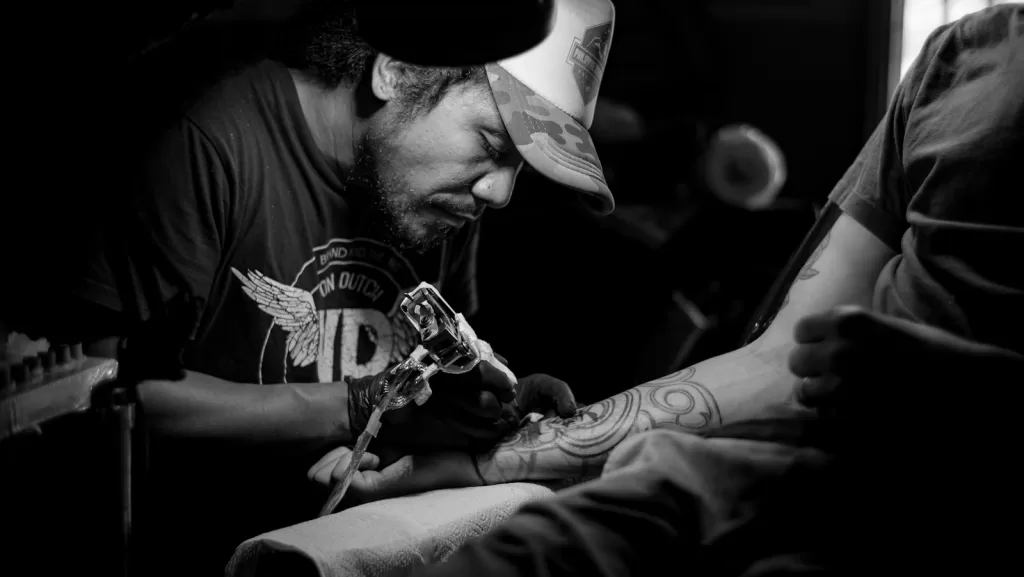 Best Tattoo Kits in India for Beginners Explained grayscale photo of man doing tattoo