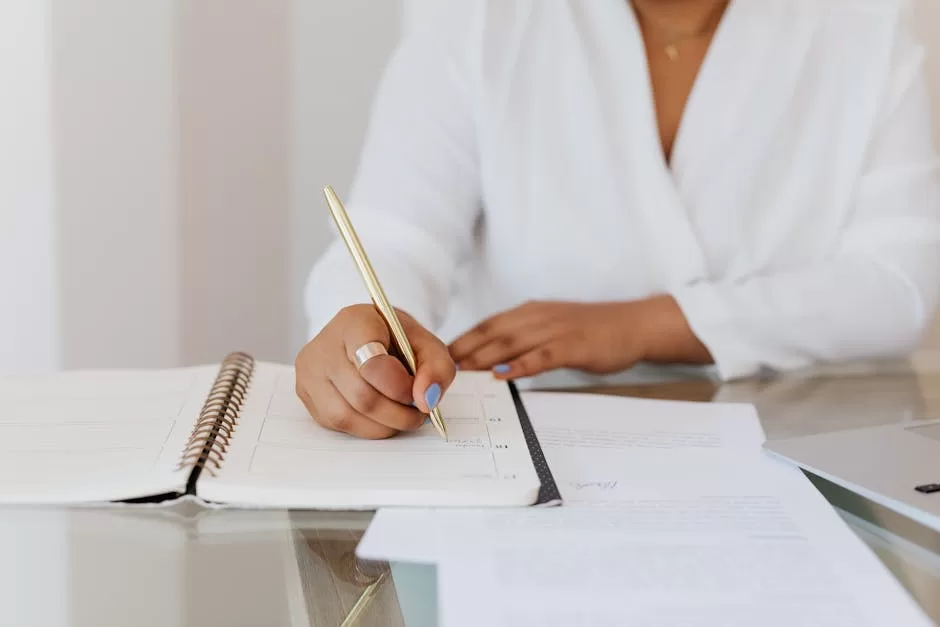 Person writing contact details in a planner with a gold pen on a clean desk, illustrating physical address books for India