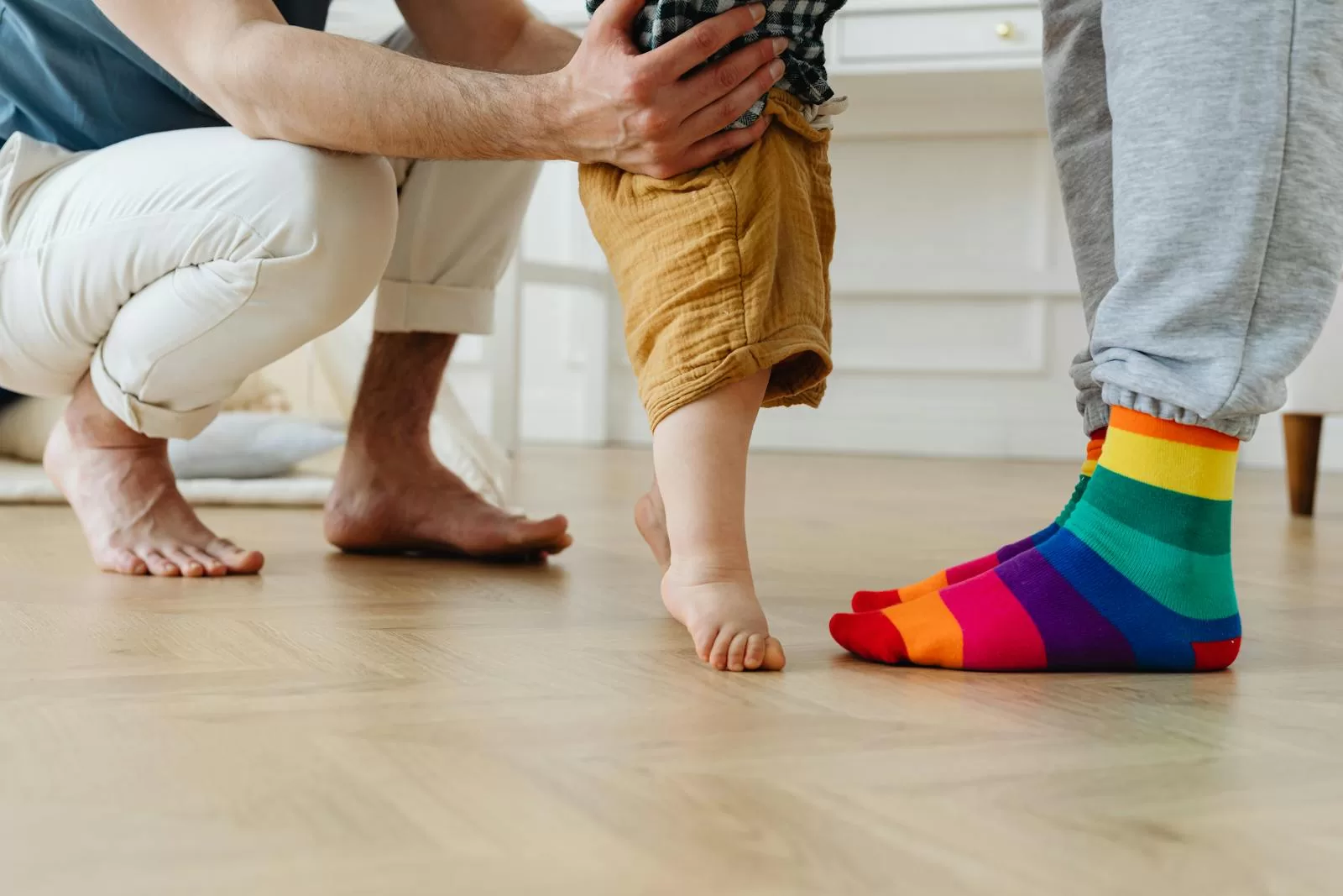 best baby walker in India - toddler taking first steps indoors with parent support on wooden floor showing the home walking transition stage