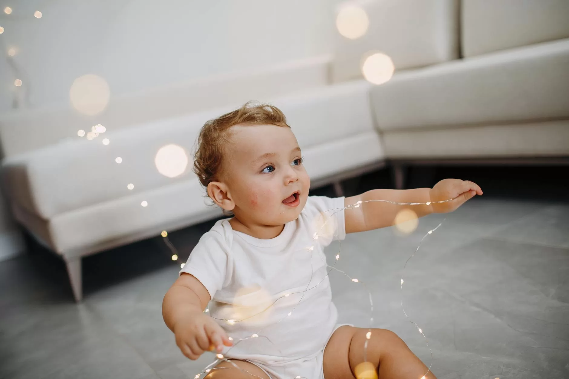 Best door bouncer in India - charming baby playing with fairy lights in a cozy living room, lifestyle home setting for babies