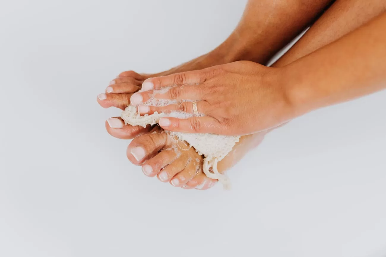 Best Spa Slippers in India: 5 Reusable & Disposable Picks for Home Pampering, Hotels & Salons Spa slippers India - washing feet with a loofah for foot hygiene, why a clean dry slipper matters between baths